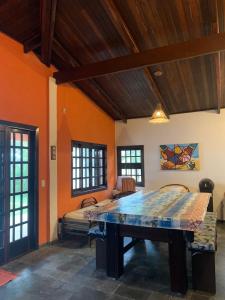 uma sala de jantar com uma mesa num quarto com paredes cor-de-laranja em Casa Pé na Areia Sapê em Ubatuba