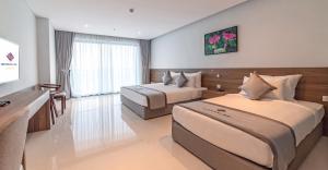 um quarto de hotel com duas camas e uma secretária em Long Thuan Hotel & Resort em Phan Rang-Tháp Chàm