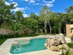 una piscina con una roca en un patio en Sasay en Puerto Aventuras