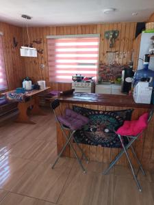 uma cozinha com uma mesa de madeira e 2 cadeiras em Cabaña Sofi em Quillón