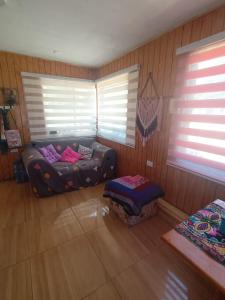 um quarto com um sofá num quarto com janelas em Cabaña Sofi em Quillón
