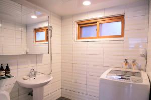 La salle de bains blanche est pourvue d'un lavabo et de toilettes. dans l'établissement SNU Stay, à Séoul