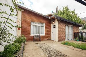 a brick house with a chair in front of it at Cabaña Robertino in El Bolsón