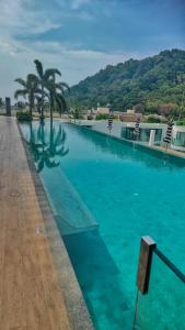 a large swimming pool with blue water and palm trees at Twin Sands Resort Penthouse in Patong Beach