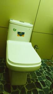 een wit toilet in een badkamer met een groene muur bij Azhar lodge koyilandy in Kozhikode