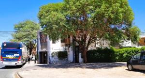 HOSTAL SyR Calama في كالاما: باص يقف امام مبنى فيه شجرة