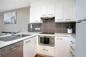 cocina blanca con fregadero y microondas en SX504 - Loftstyle One Bedroom in the Heart of CBD en Sídney