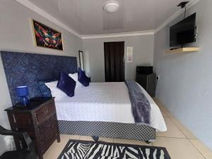 een slaapkamer met een bed met blauwe kussens bij Black Owl Lodge in Kempton Park