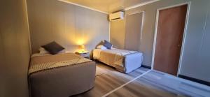 um pequeno quarto com 2 camas e uma cadeira em HOSTAL SyR Calama em Calama
