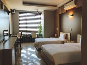 ドンホイにあるKhách sạn 20-10 Quảng Bìnhのベッド2台とデスクが備わるホテルルームです。