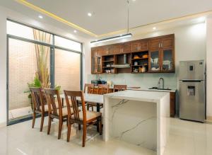 La cuisine est équipée d'une table, de chaises et d'un réfrigérateur. dans l'établissement Sunset Pool Villa 4BR, New, Full AC, walk to beach, à Đà Nẵng