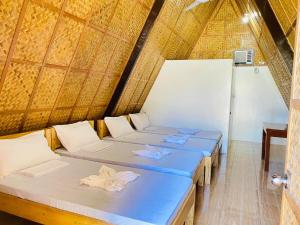 a group of four beds in a thatched room at Casa Gracia's Hotel and Restaurant in San Aquilino