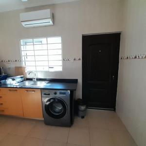 a kitchen with a washing machine and a sink at Chateau Eyram in Accra