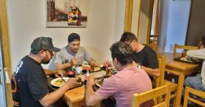 un grupo de hombres sentados alrededor de una mesa comiendo comida en HOSTAL SyR Calama en Calama