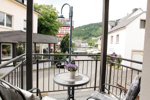 - un balcon avec une table et des fleurs dans l'établissement JG-Haus Ferienwohnungen, à Bullay
