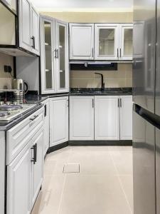 cocina con armarios blancos y nevera de acero inoxidable en GR - A quiet bedroom apartment 9 en Riad
