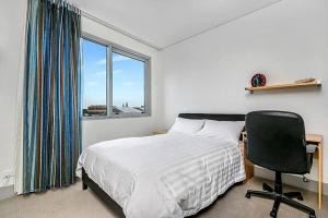 a bedroom with a bed and a chair and a window at CBD Chinese Gardens Views, Modern 2BR Apt SX339 in Sydney