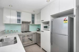 a white kitchen with a refrigerator and a sink at CBD Chinese Gardens Views, Modern 2BR Apt SX339 in Sydney