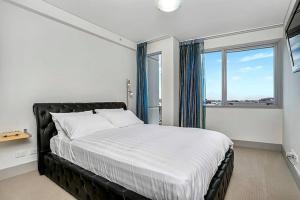 a bedroom with a large bed with a large window at CBD Chinese Gardens Views, Modern 2BR Apt SX339 in Sydney