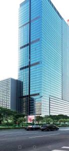 two cars driving in front of a large glass building at East Maple International Apartment - Guangzhou International Financial City Keyun Road Metro Station in Guangzhou