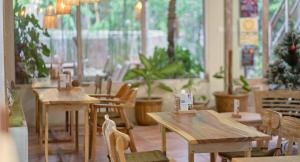 un restaurante con mesas de madera, sillas y plantas en Risna Homestay en Lembongan