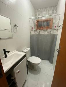 a white bathroom with a toilet and a sink at Aconchego da praia in Capão da Canoa