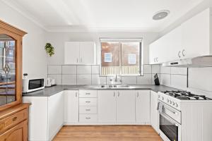 a white kitchen with a sink and a stove at Premier Leichhardt Stayz in Sydney