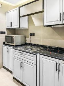 a kitchen with white cabinets and a microwave at GR - A quiet bedroom apartment 10 in Riyadh
