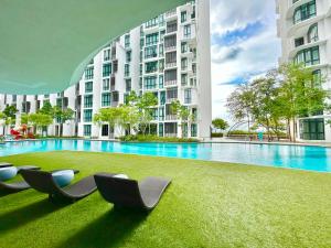 - une piscine avec des chaises longues devant un bâtiment dans l'établissement 1-8 pax Comfort Place 3room Ara Damansara, à Petaling Jaya