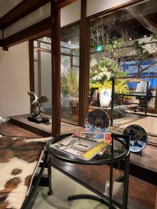 una sala de estar con una mesa de cristal y una habitación con ventanas en 史跡旅館 花月大正館 en Takeo