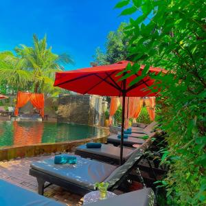 un grupo de sillas y una sombrilla junto a una piscina en Central Privilege Hotel en Siem Riep