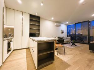 a kitchen with white cabinets and a living room at 1 BRM 1 Study 1 BATH, Southern Cross Station, Flagstaff Garden in Melbourne