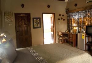 a bedroom with a bed and a desk and a kitchen at Four Villages Inn in Kumasi