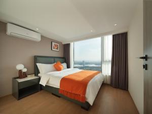 a bedroom with a bed and a large window at East Maple Hotel Apartment - Guangzhou Financial City Sanxi Metro Station in Guangzhou