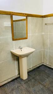 a bathroom with a white sink and a mirror at Sigiriya Chena Villa in Sigiriya