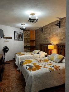 ウアスカ・デ・オカンポにあるHotel Huasca Terrazzaのレンガの壁、ベッド2台が備わるベッドルーム1室が備わります。