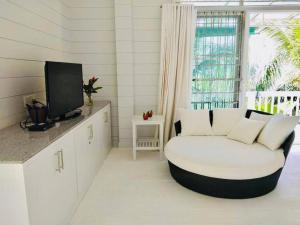 een witte woonkamer met een bank en een tv bij The Sunny Hill Pool Villa 180° Panoramic Sea View 