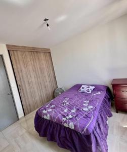 1 dormitorio con cama morada y edredón morado en Alojamiento completo, en San Isidro de los López