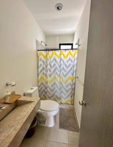 a bathroom with a toilet and a shower curtain at Alojamiento completo in San Isidro de los López