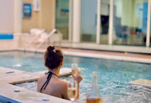 une femme assise dans une piscine pour boire un verre dans l'établissement Green Coast Resort & Residences 94, à Palasë