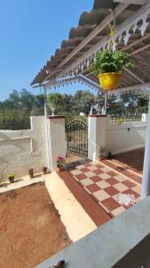 a pergola with a potted plant on a checkered patio at Sri Krishna Cottage in Yelagiri