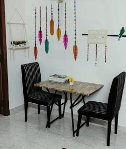 a dining room table with two chairs and a birdendant at Sri Krishna Cottage in Yelagiri