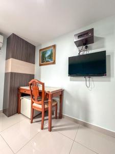 a room with a desk and a chair and a television at G Star Hotel in Pantai Remis