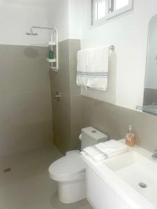a white bathroom with a toilet and a sink at Casa Lobster Bay in Ayangue