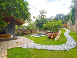 einen Garten mit einem Felspfad und einem Pool in der Unterkunft M60 Feet Villa in Madihe East