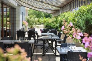 an outdoor patio with tables and chairs and flowers at Kyriad Saint-Etienne Centre in Saint-&Eacute;tienne