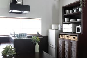 a kitchen with a white refrigerator and a counter at 城崎温泉一棟貸し　旅宿YaDOKARI in Toyooka