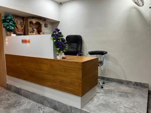 a reception desk with a black chair and flowers at Hotel Savariya Palace in Ahmedabad