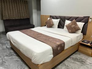 a bedroom with a large bed with a wooden headboard at Hotel Savariya Palace in Ahmedabad
