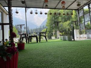 a room with a green floor with a table and chairs at OYO Hotel Rohtang View in Manāli